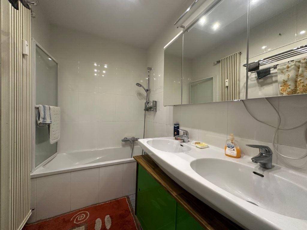 Badezimmer mit Doppelwaschbecken, Badewanne und Duschfunktion.
