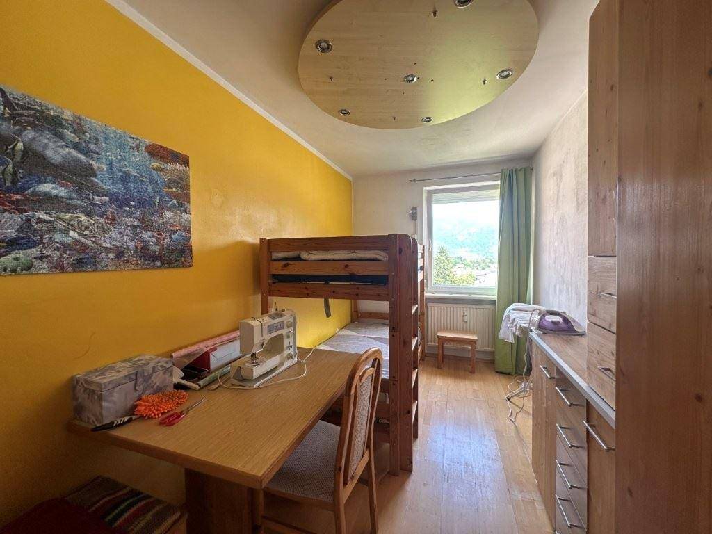 Helles Kinderzimmer mit Etagenbett, Schreibtisch und gelber Akzentwand.