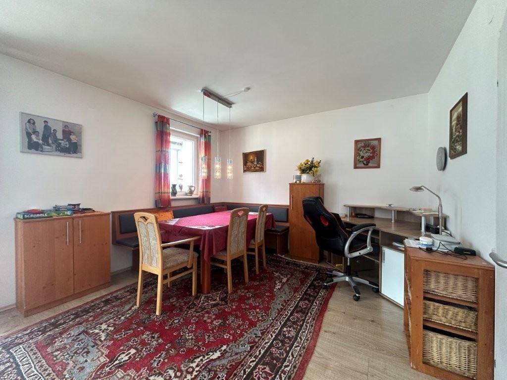 Essbereich mit Eckbank und Teppichboden, kombiniert mit einem Arbeitsplatz.