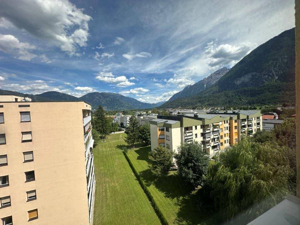 Weitläufige Grünflächen zwischen Wohngebäuden mit Bergblick im Hintergrund.