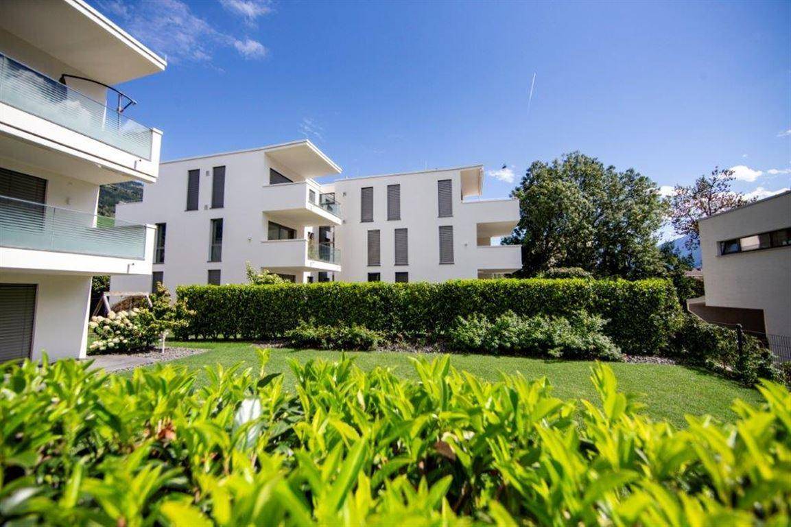 Gepflegter Gemeinschaftsgarten mit Rasenflächen, Hecken und Blick auf die Wohngebäude.