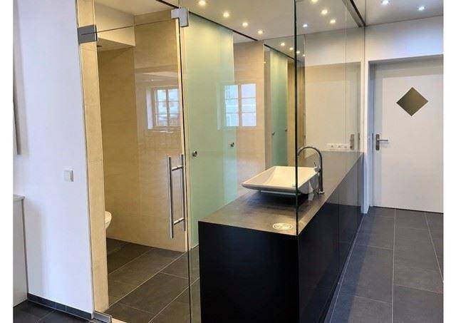 Modernes Badezimmer mit begehbarer Dusche, Glaswänden und stilvollem Aufsatzwaschbecken.