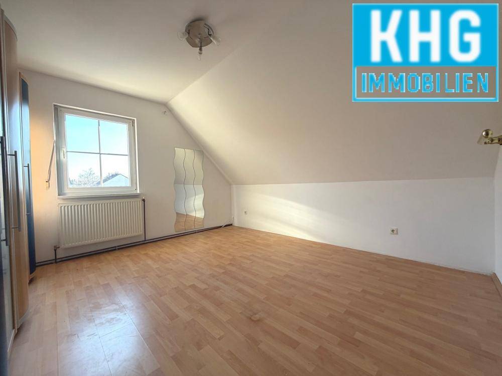 Helles Dachgeschosszimmer mit Dachschräge und Laminatboden.