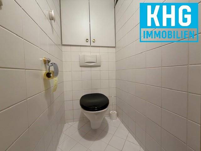 Kleines separates WC mit weißen Fliesen an Wänden und Boden.