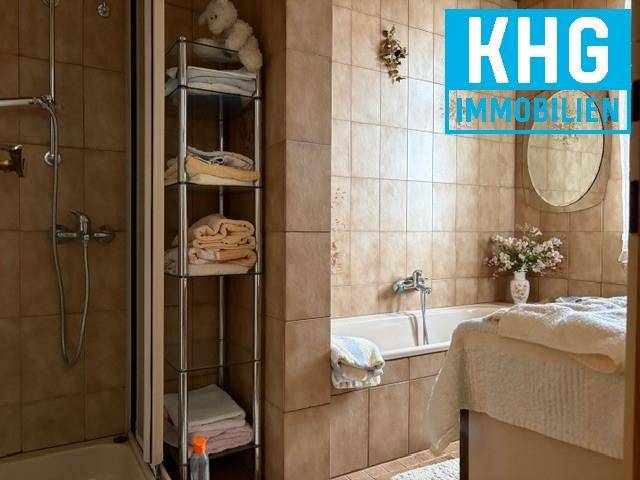 Badezimmer mit Badewanne, Dusche und braunen Fliesen im traditionellen Stil.