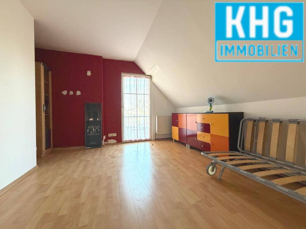 Dachgeschosszimmer mit Dachschräge, Laminatboden und farbiger Wand.
