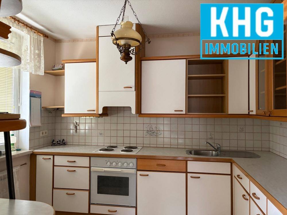 Funktionale Küche mit weißen Schränken, Fliesenrückwand und Kochfeld.
