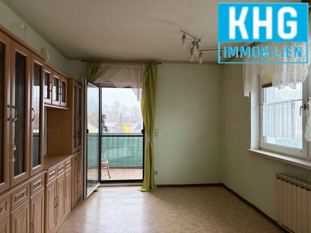 Wohnbereich mit Einbauschränken, Blick ins Grüne und Zugang zum Balkon.