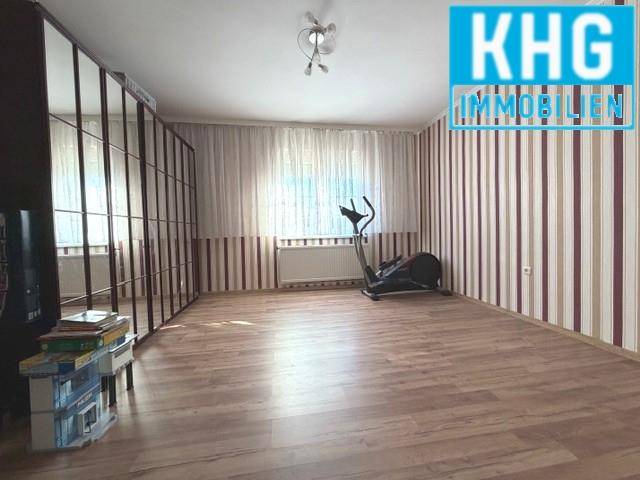 Geräumiges Zimmer mit Laminatboden und gestreiften Tapeten.