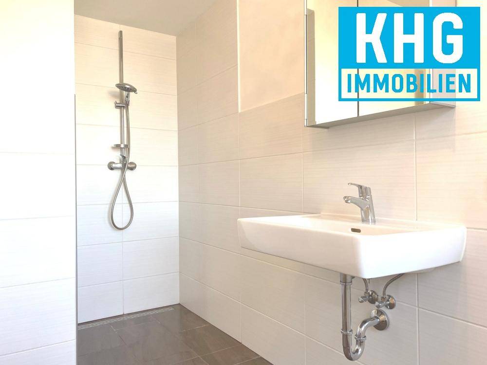 Modernes Badezimmer mit ebenerdiger Dusche, Waschbecken und Spiegelschrank.