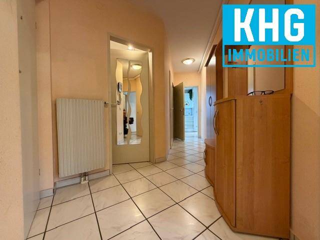 Heller Flur mit Fliesenboden, Holzmöbeln und Zugang zu weiteren Räumen.