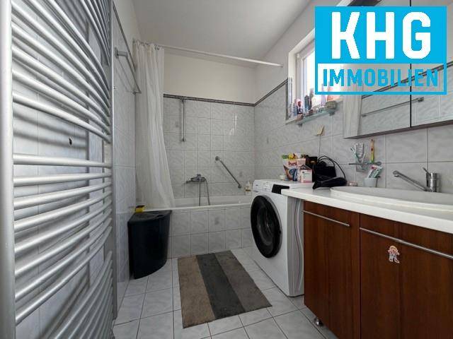 Badezimmer mit Badewanne, Waschmaschine und beheiztem Handtuchhalter.