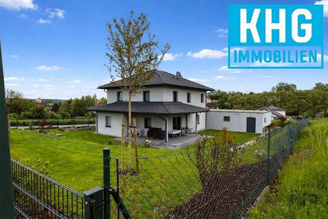 Weitläufiger Blick auf das moderne Einfamilienhaus mit großem Garten und ländlicher Umgebung.