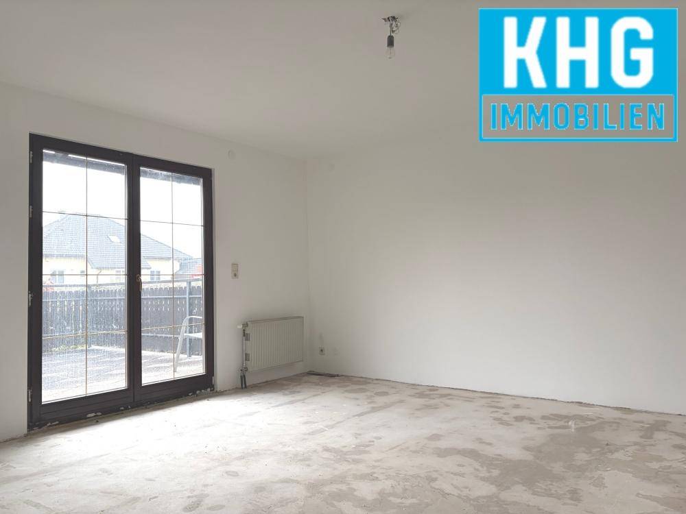 Heller, leerer Raum mit großen Fenstertüren und Betonboden, bereit für individuelle Gestaltung.