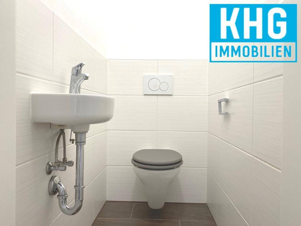 Separates Gäste-WC mit wandhängender Toilette und kleinem Handwaschbecken.