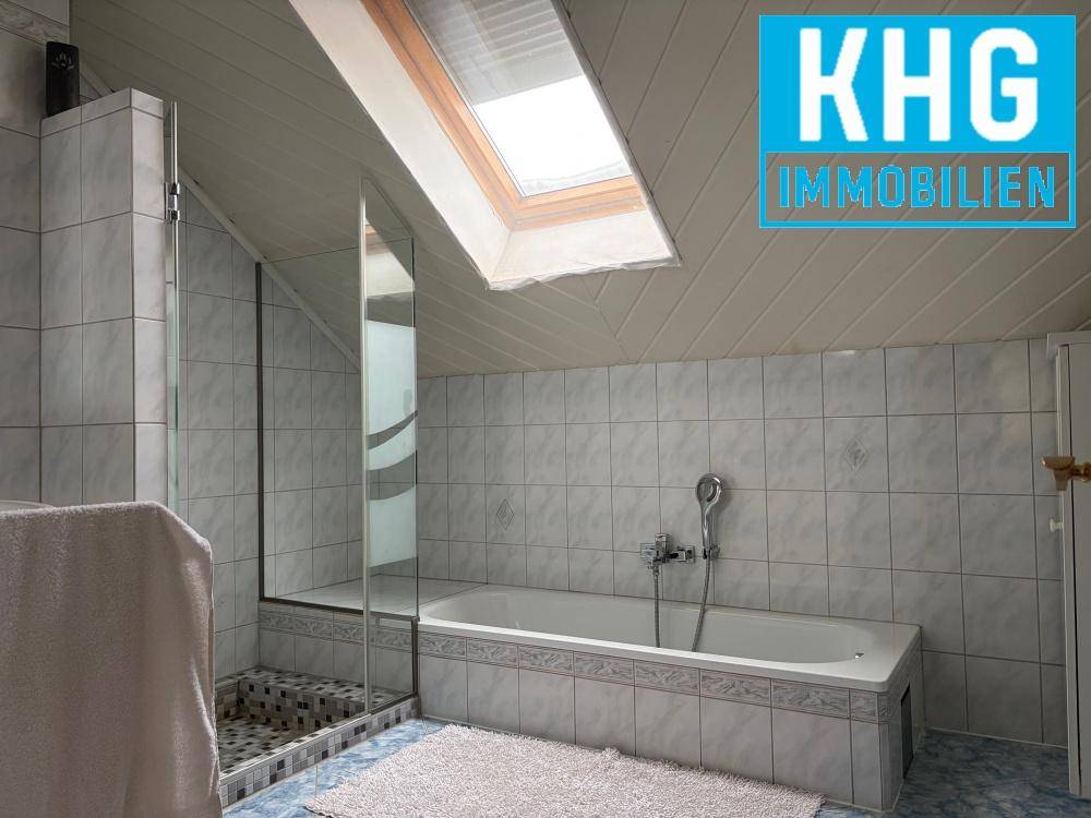 Helles Badezimmer im Dachgeschoss mit Badewanne, Dusche und Dachfenster.
