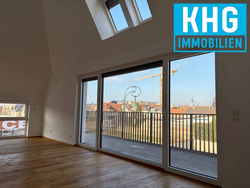 Heller Wohnbereich mit Holzboden, großen Schiebetüren zum Balkon und Dachfenstern.