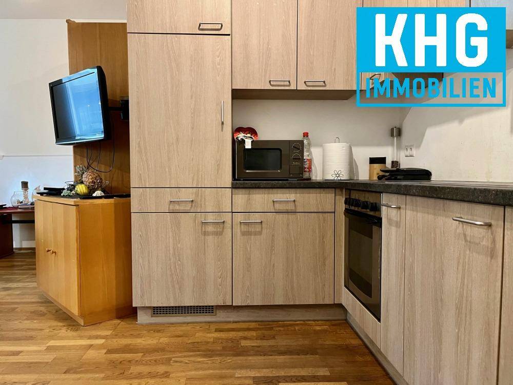 Küche mit weiteren Holzschränken, Mikrowelle und Kühlschrank.