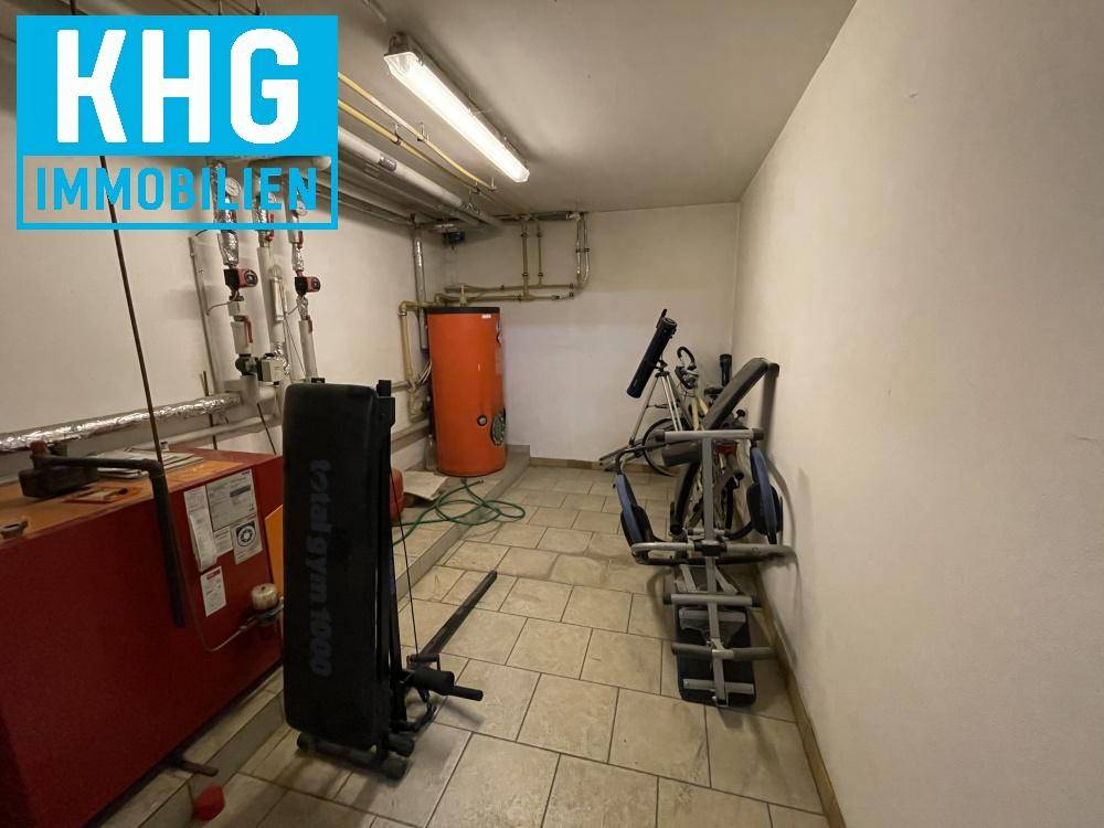 Heizungsraum im Keller mit Warmwasserspeicher und Fitnessgeräten, multifunktional genutzt.