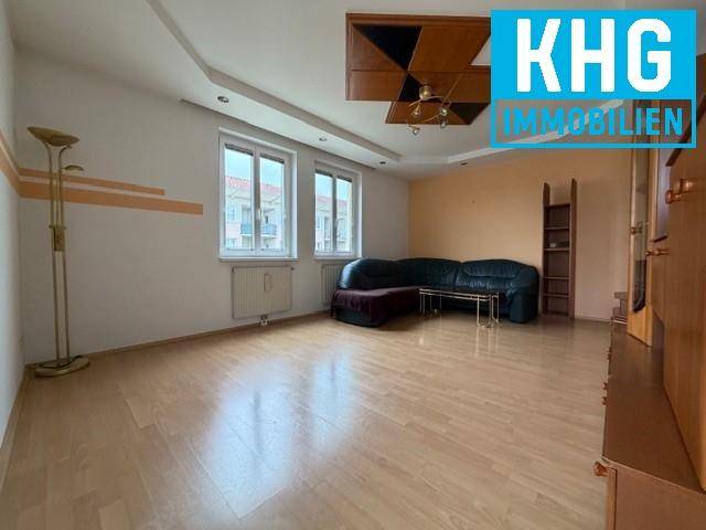 Geräumiges Wohnzimmer mit Parkettboden, großen Fenstern und dekorativer Decke.