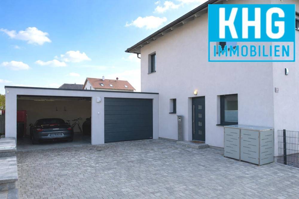 Eingangsbereich des modernen Einfamilienhauses mit Doppelgarage und gepflasterter Auffahrt.