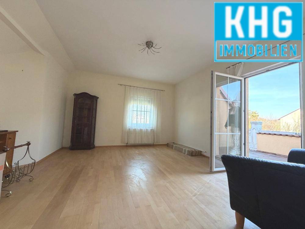 Helles Zimmer mit Zugang zum Balkon und Parkettboden.