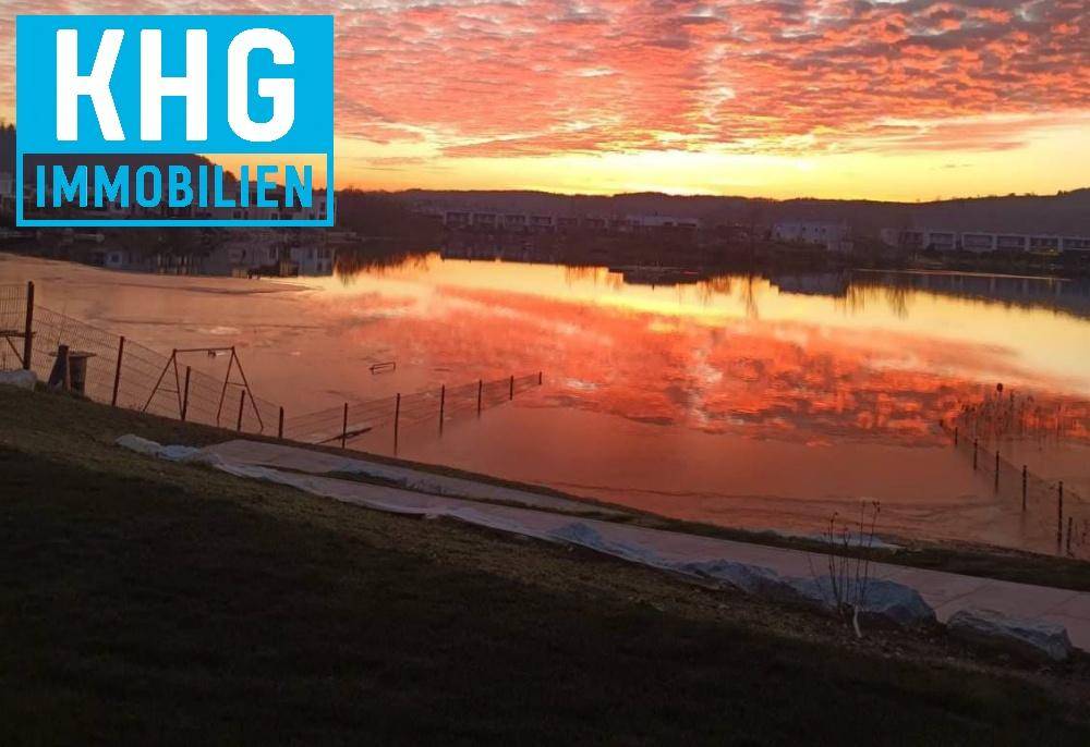 Spektakulärer Sonnenuntergang über dem See, der den Himmel und das Wasser in leuchtenden Farben färbt.