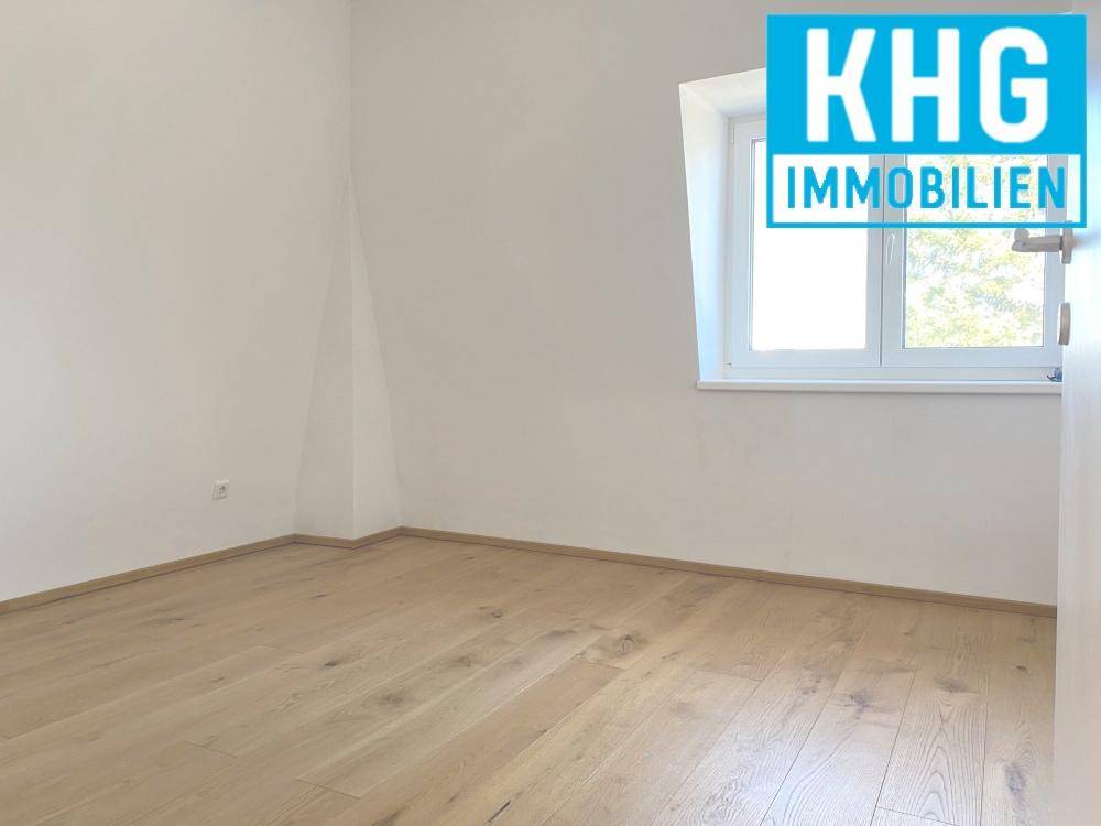 Helles Schlafzimmer mit Holzboden, weißen Wänden und Fenster in der Dachschräge.