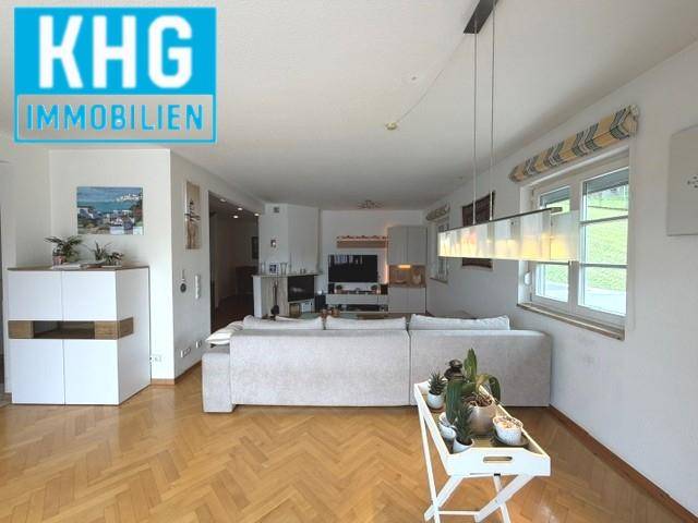 Helles Wohnzimmer mit Fischgrätparkett und großen Fenstern, modern eingerichtet.