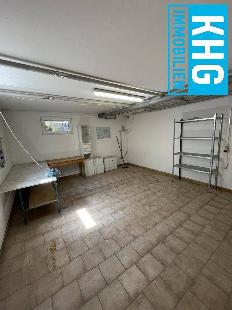 Heller Kellerraum mit Werkbank und Regalen, bietet viel Platz für handwerkliche Tätigkeiten.