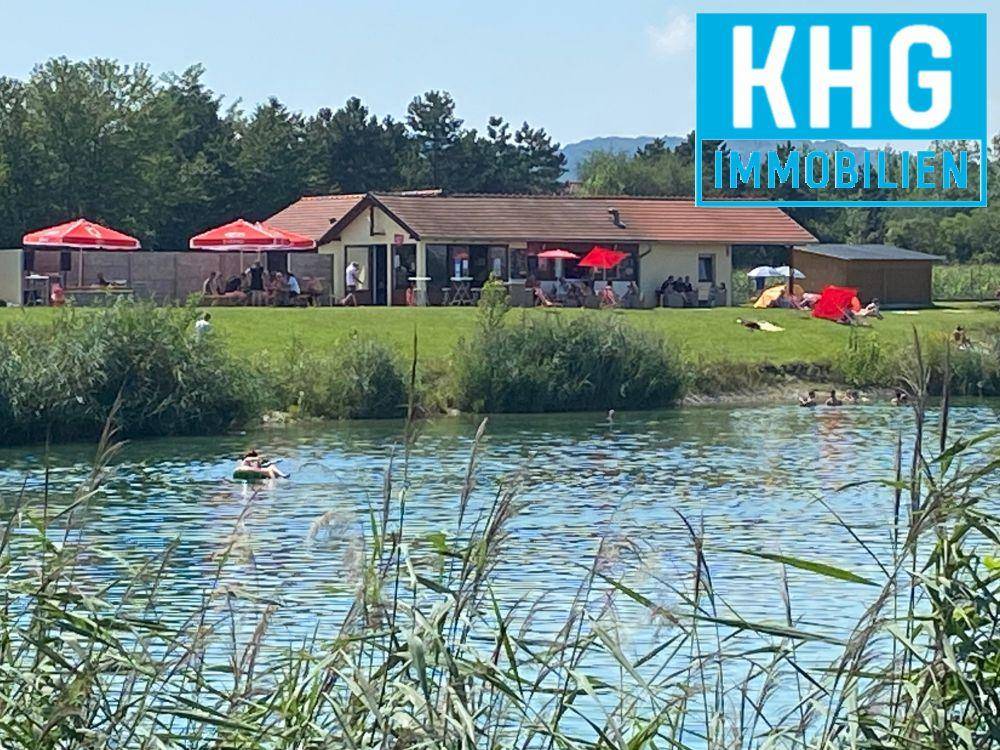 Blick auf einen See mit einem Gebäude am Ufer, wo Menschen schwimmen und sich entspannen.