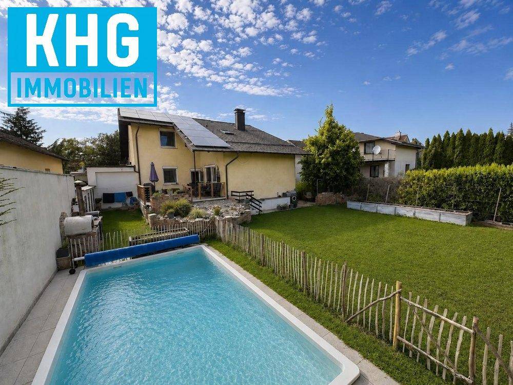 Hinteransicht des Hauses mit großem Garten, Swimmingpool und Solarpaneelen auf dem Dach.