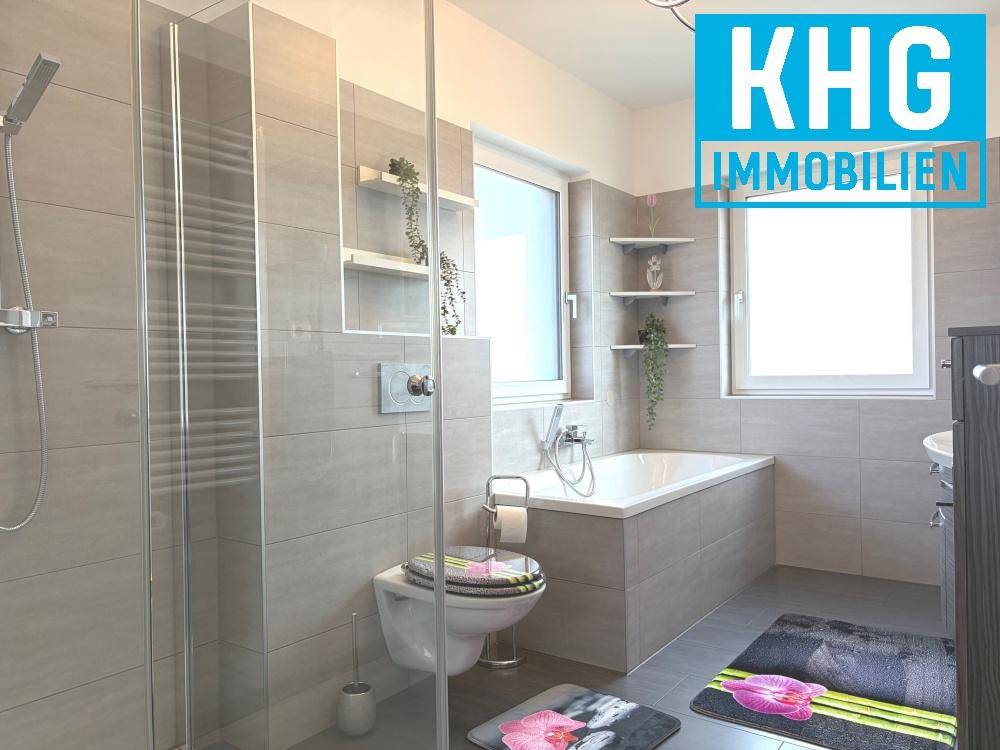 Modernes Badezimmer mit Badewanne, ebenerdiger Dusche und Fenster für Tageslicht.
