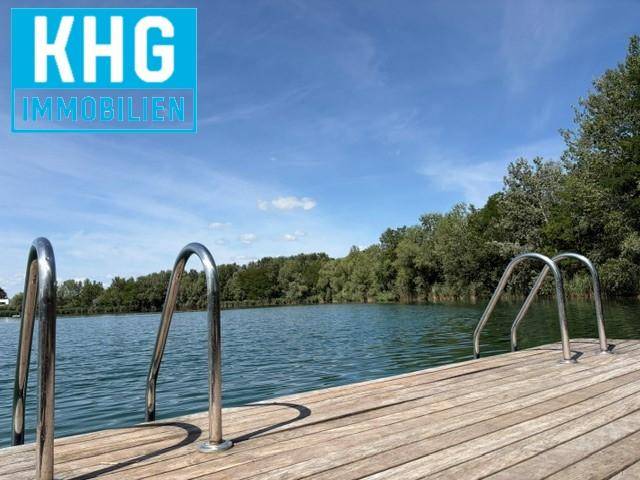 Holzsteg mit Metallhandläufen führt direkt ins klare Wasser des Sees unter blauem Himmel.