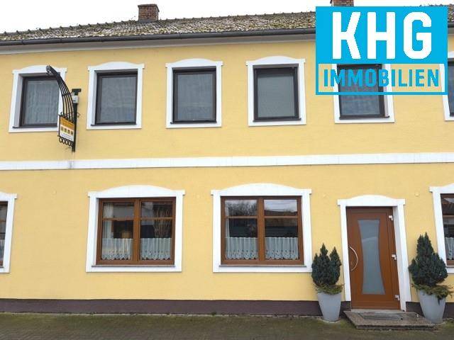 Gelbe Fassade eines traditionellen Gebäudes mit mehreren Fenstern und einem Eingangsbereich.