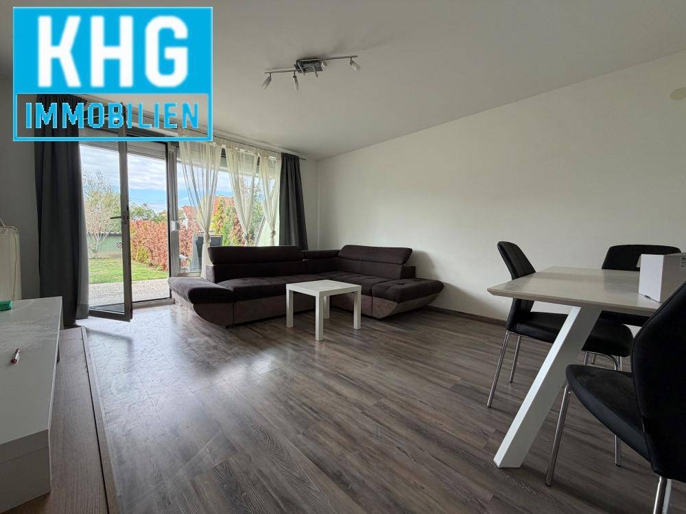 Offener Wohn-Essbereich mit Laminatboden, Sofa und Zugang zum Garten.
