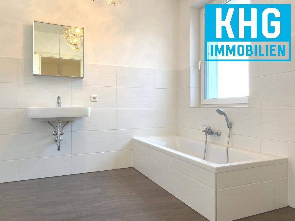 Modernes Badezimmer mit Badewanne, Waschbecken, Spiegelschrank und Fenster.