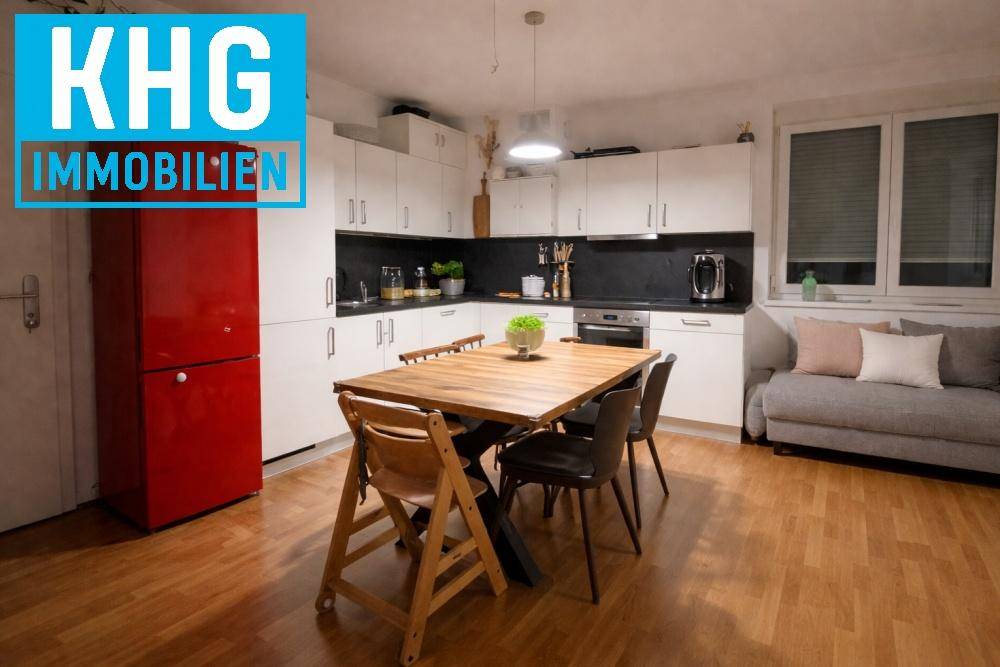 Moderne Einbauküche mit weißen Schränken, Esstisch und rotem Kühlschrank.