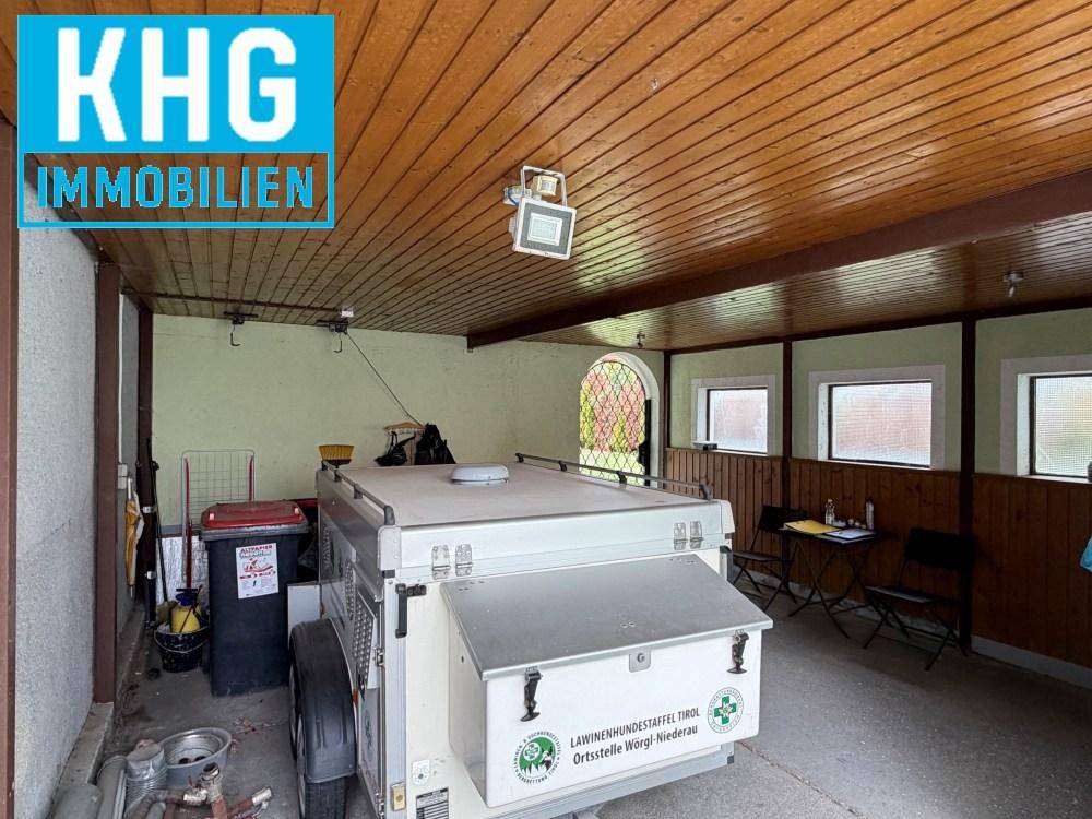 Geräumige Garage mit Holzdecke, Betonboden und kleinen Fenstern.