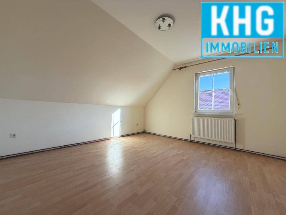 Dachgeschosszimmer mit Dachschräge, Fenster und Laminatboden.