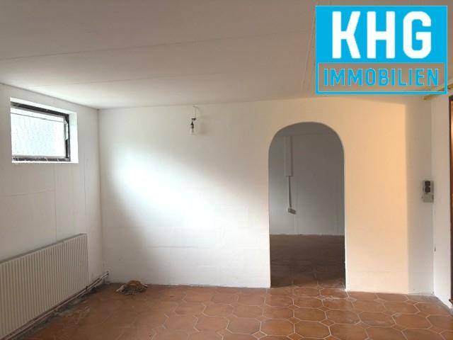 Einfacher Raum mit Heizkörper, kleiner Fensteröffnung und einem Durchgang mit Rundbogen.