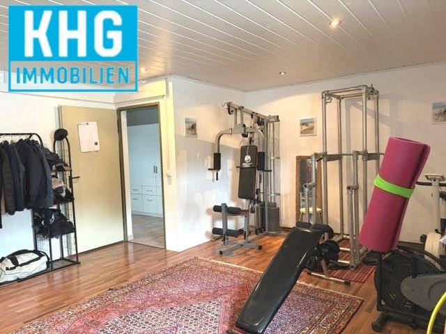 Privater Fitnessraum mit verschiedenen Trainingsgeräten und Holzboden.
