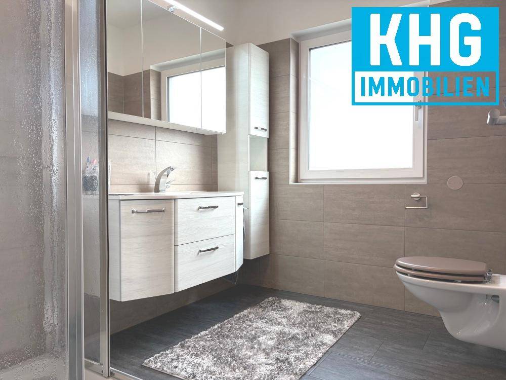 Helles Badezimmer mit modernem Waschtisch, Spiegelschrank und Fenster.