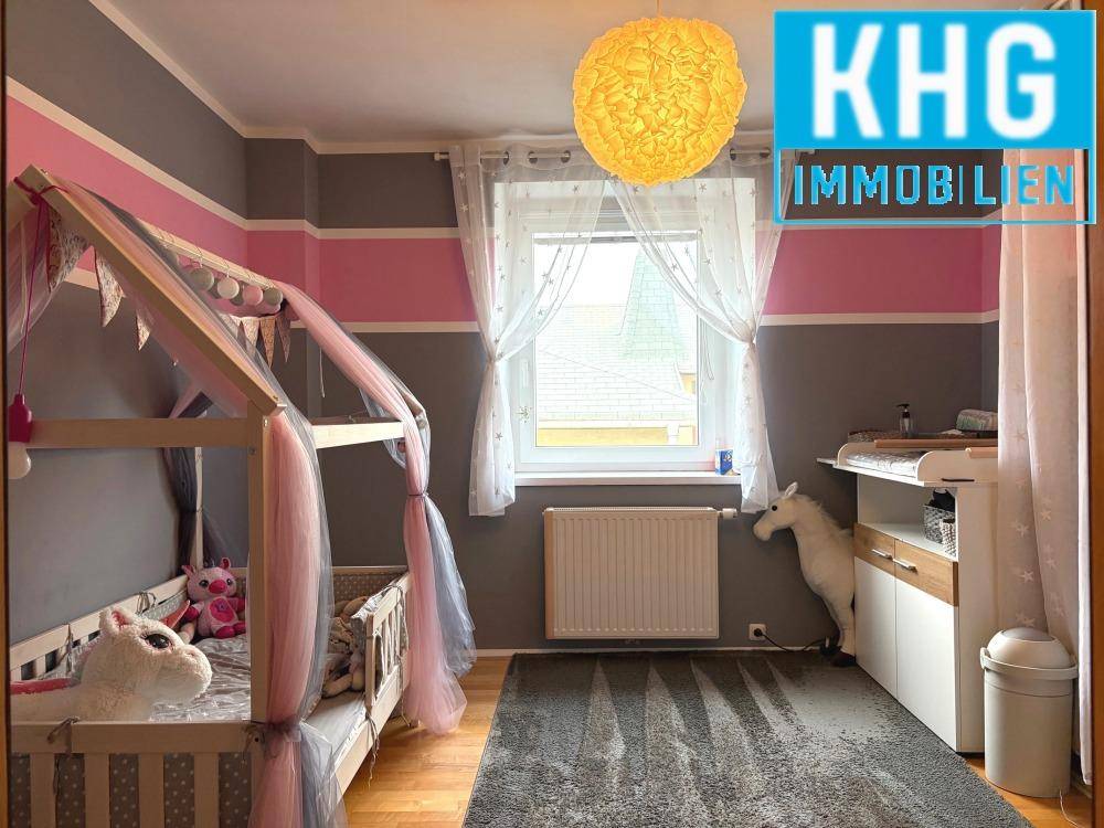Kinderzimmer mit Holzboden, Wickeltisch und farbenfroher Wandgestaltung.