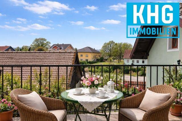 Gemütlicher Balkon mit Korbmöbeln, Tisch und Blumen, bietet einen weiten Blick.
