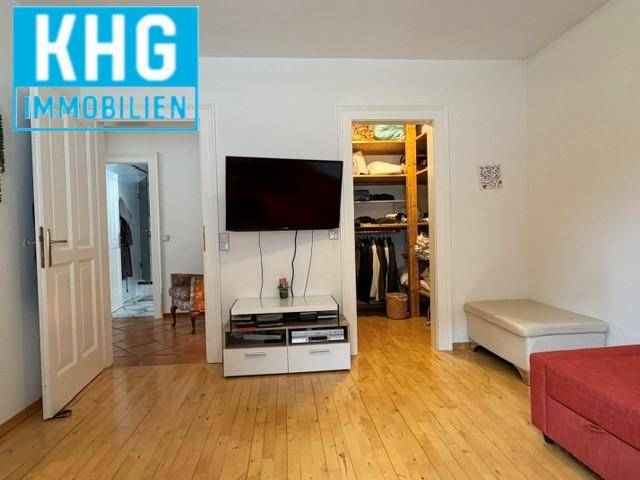 Schlafzimmer mit Holzboden und Zugang zu einem begehbaren Kleiderschrank.