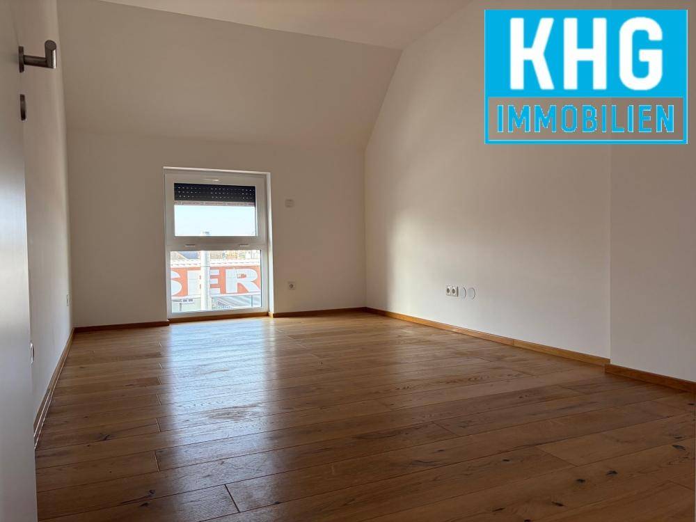 Geräumiges Schlafzimmer mit Holzboden und einem Fenster, das viel Tageslicht hereinlässt.