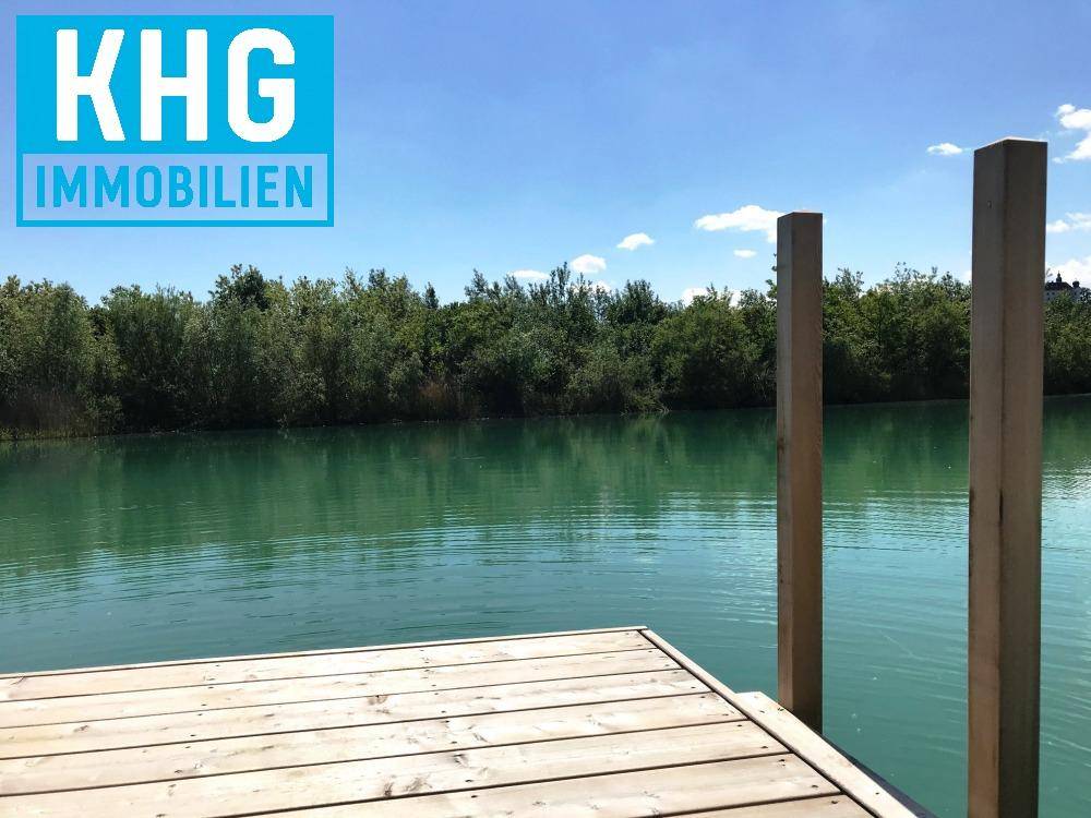Holzsteg ragt in einen ruhigen, türkisfarbenen See, umgeben von üppiger Vegetation.