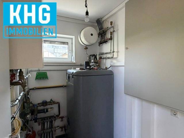 Funktionaler Hauswirtschaftsraum mit Warmwasserspeicher, Rohrleitungen und einem kleinen Fenster.