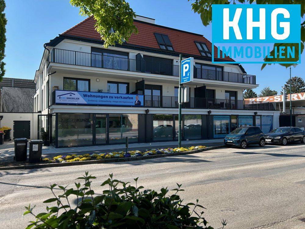 Modernes Mehrfamilienhaus mit Geschäften im Erdgeschoss und Balkonen in städtischer Umgebung.